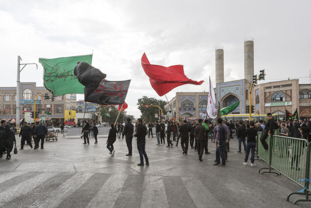 Young men waving flags during a public procession in Iran