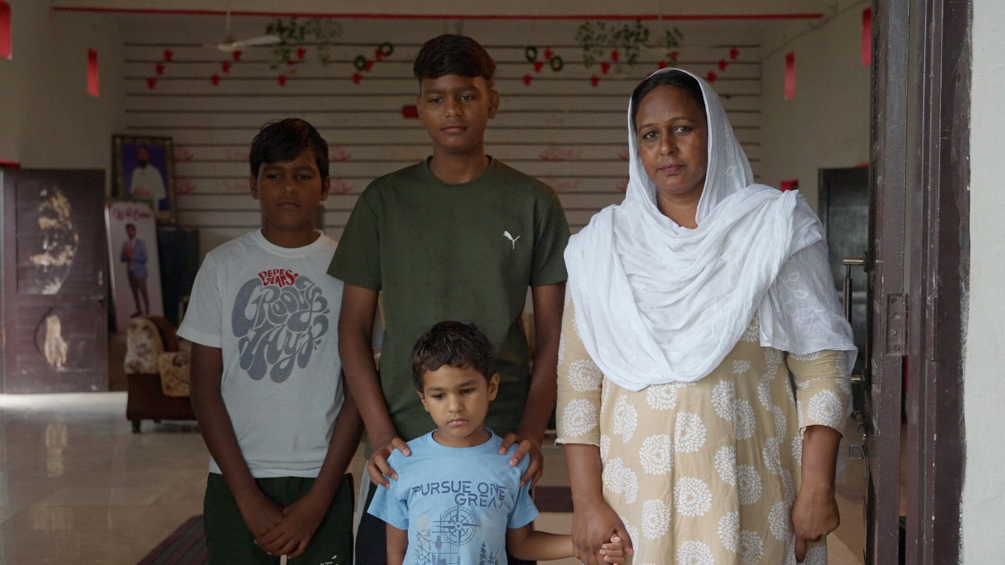 Simran standing in her church doorway with her sons