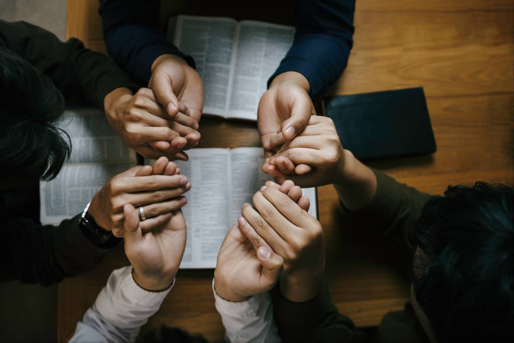 A prayer group holding hands