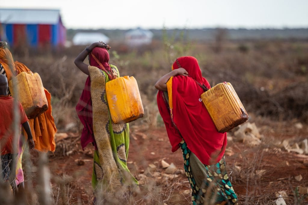 Girls in Somalia carrying water in plastic drums.