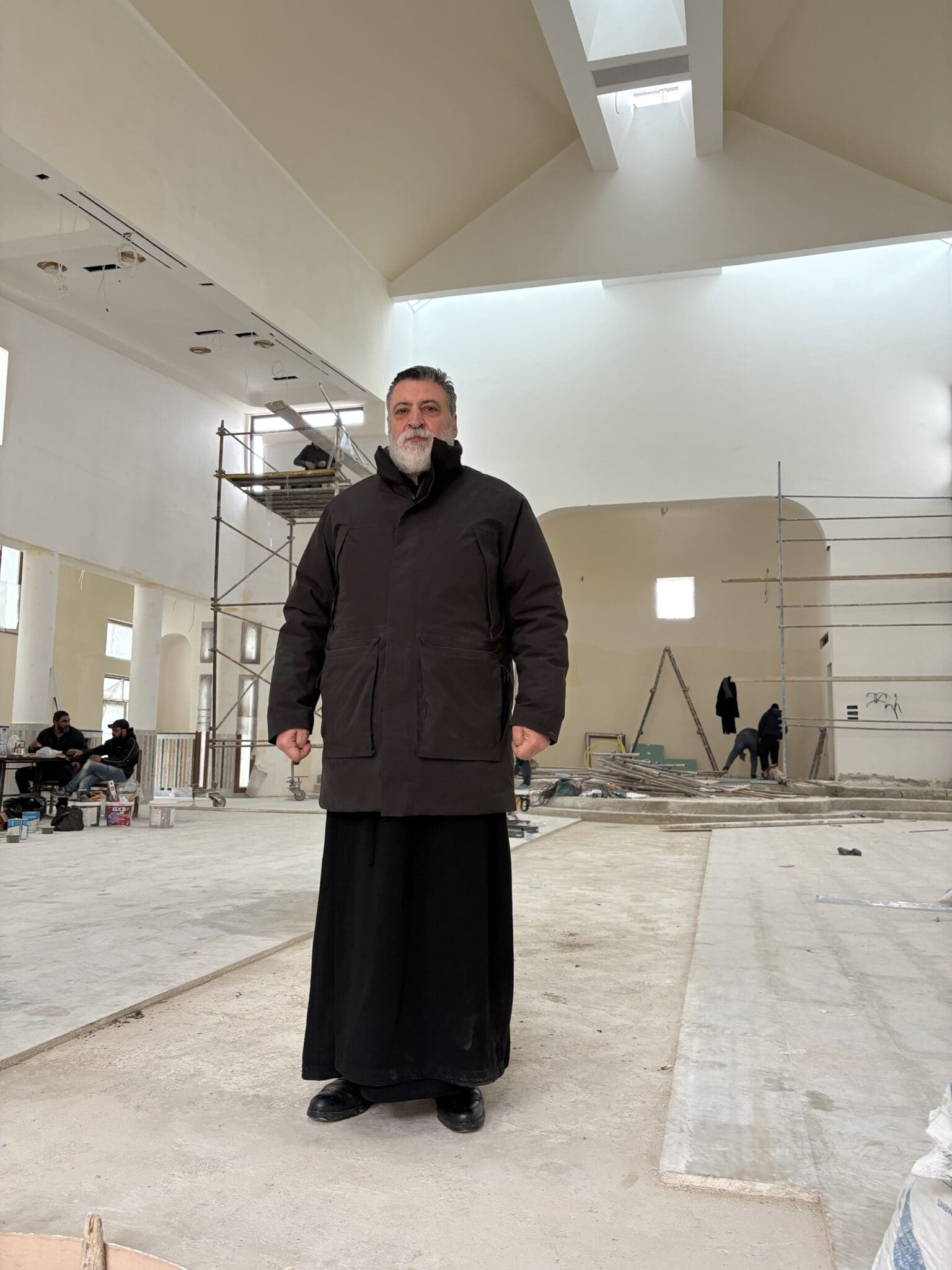 Father Boutrous stands inside Mar Elias Church, mid-renovation